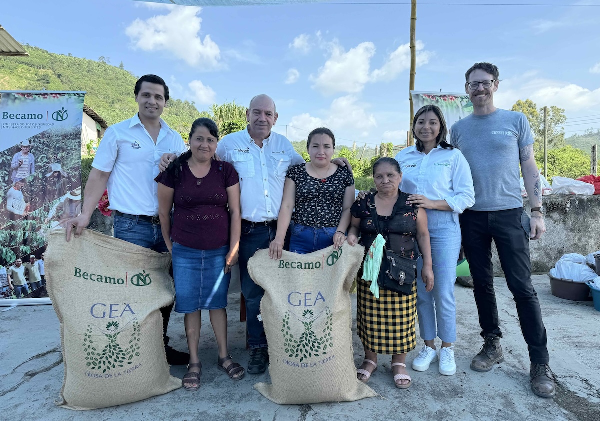 Women coffee producers pose with their bags of coffee. 